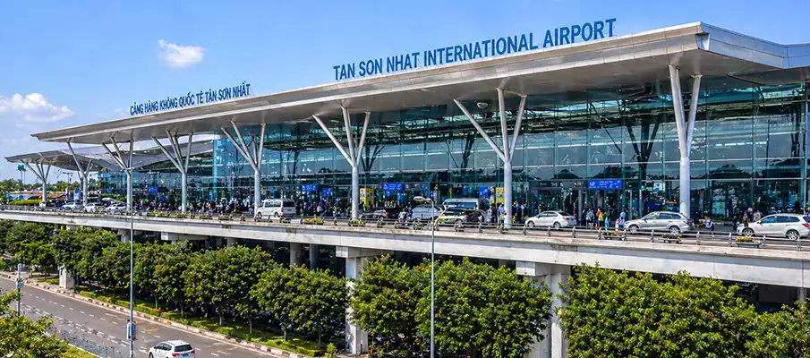 Hlavní terminál letiště Tan Son Nhat s prosklenou fasádou a dopravou před budovou, Vietnam